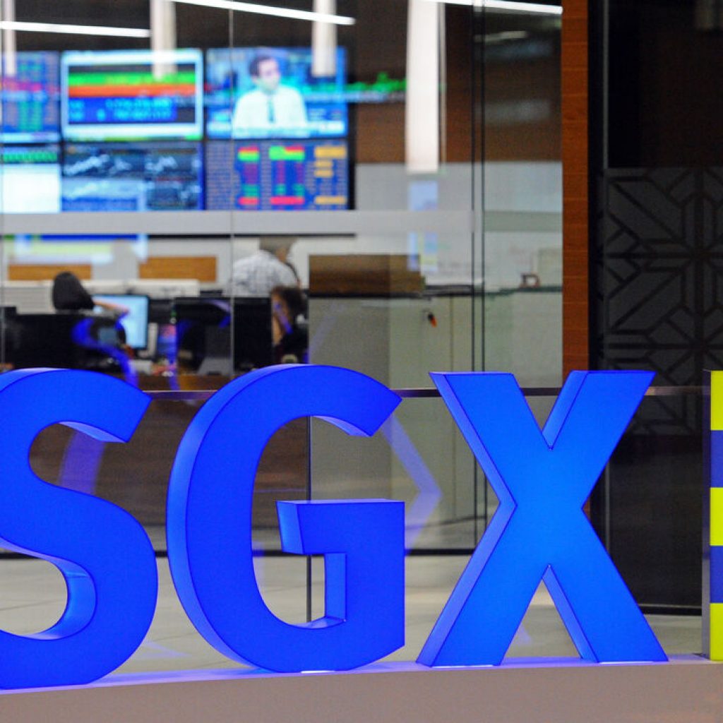 A staff member walks past blue and yellow SGX office signage in Singapore Exchange (SGX).