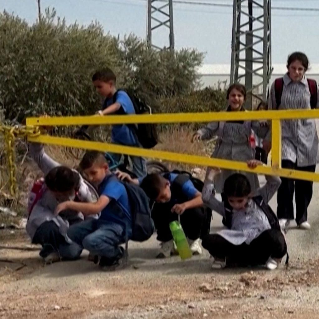 Palestinian children crawl under Israeli military gates to
get to school